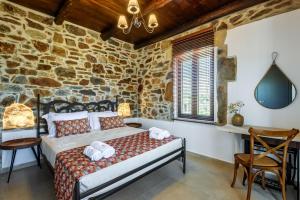 a bedroom with a bed and a stone wall at Minos Country Living Apartments in Agrilés