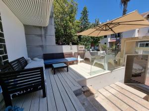 una terrazza in legno con tavolo e ombrellone di וילה אברמוביץ a Rishon LeẔiyyon