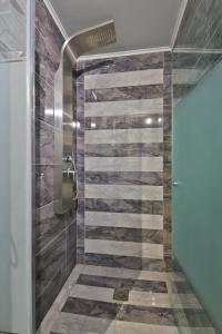a bathroom with a shower with a stone wall at Fotini Studios in Paleokastritsa