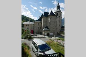 un coche blanco estacionado frente a un castillo en Joli appartement confortable rénové style cosy, en Saint-Martin-de-la-Porte