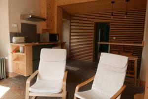 2 sillas blancas en una habitación con cocina en Joli appartement confortable rénové style cosy, en Saint-Martin-de-la-Porte