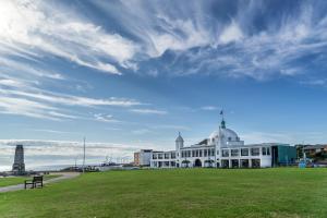 a white building with a grass field in front of it at Seahawk Lodge in Whitley Bay