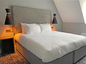 a bedroom with a bed with white sheets and two lamps at 1820 Boutique Rooms & Suites in Blackpool