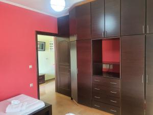 a room with wooden cabinets and a red wall at Mihal Suites in Sarandë