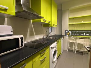 eine Küche mit hellgrünen Schränken und einer Mikrowelle in der Unterkunft HomyAT Prior Romo, Plaza Mayor in Salamanca