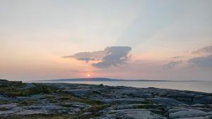una puesta de sol en la orilla de un cuerpo de agua en Lios Éinne House Accommodation, en Inis Oírr