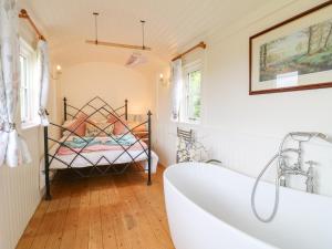 a bathroom with a bath tub and a bed at Shepherds Hut in Rugeley