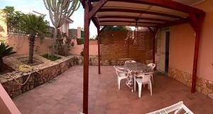a patio with a table and chairs under a pergola at Lopadusa trilo 1 in Lampedusa