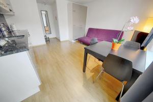 sala de estar con mesa y sofá púrpura en HITrental Letzigrund - Apartment, en Zúrich