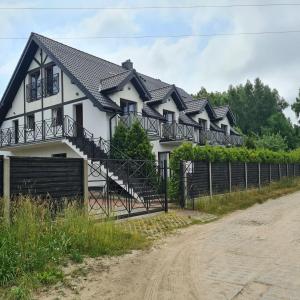 una casa blanca con techo negro y un camino de tierra en Baltic Trio Apartaments - Rusinowo, en Rusinowo