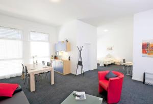 sala de estar con silla roja y mesa en HITrental Zugersee -Apartments, en Zug