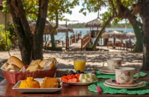 a table with plates of bread and cups of orange juice at Pousada Flambaião in Jijoca de Jericoacoara