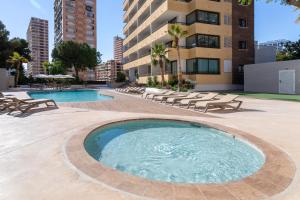 a swimming pool with lounge chairs and a building at Halley Hotel & Apartments Affiliated by Meliá in Benidorm