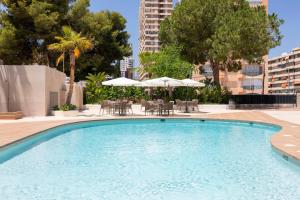 a swimming pool with tables and chairs and umbrellas at Halley Hotel & Apartments Affiliated by Meliá in Benidorm