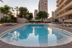 a large swimming pool with chairs and a building at Halley Hotel & Apartments Affiliated by Meliá in Benidorm