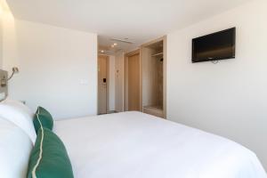 a bedroom with a white bed and a flat screen tv at Halley Hotel & Apartments Affiliated by Meliá in Benidorm