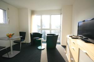 a room with a tv and a table and chairs at HITrental Zugersee -Apartments in Zug