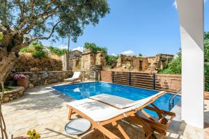 a villa with a pool and a table and chairs at Minos Country Living Apartments in Agrilés