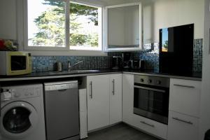 a kitchen with white cabinets and a washer and dryer at Charmante maison à 500 m de la côte, pour 4 in Notre-Dame-de-Monts