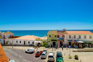 a street in a town with cars parked on the street at Pé na Praia by OCvillas in Albufeira