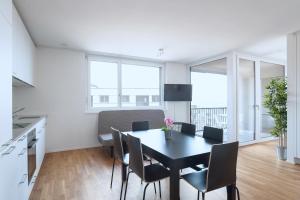 cocina y comedor con mesa y sillas en HITrental Messe Apartments, en Basilea