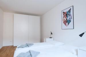a white bedroom with a bed and a painting on the wall at HITrental Basel Apartments in Basel +66 photos