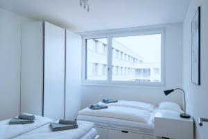 a white room with two beds and a window at HITrental Basel Apartments in Basel