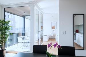 a dining room with white walls and a large mirror at HITrental Basel Apartments in Basel