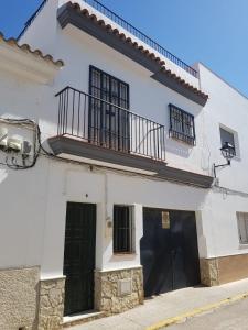 ein weißes Haus mit schwarzen Türen und einem Balkon in der Unterkunft Apartamento Antonio Machado in Barbate