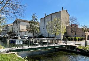a bridge over a river in front of a building at Quai du Félibre in LʼIsle-sur-la-Sorgue