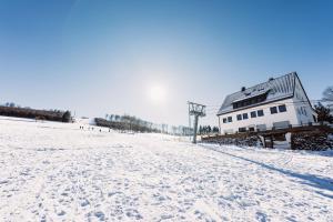 een met sneeuw bedekt veld met een huis op de achtergrond bij Q-Stall am Poppenberg in Brilon