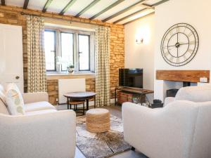 a living room with white furniture and a clock on the wall at Well Cottage in Cheltenham