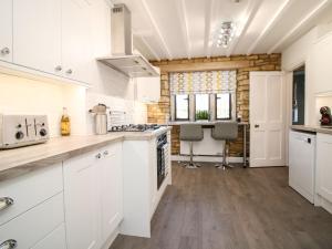 a kitchen with white cabinets and wooden floors at Well Cottage in Cheltenham