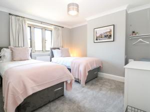 a bedroom with two beds and a window at Well Cottage in Cheltenham