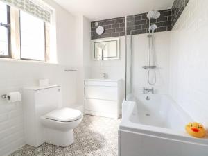 a white bathroom with a toilet and a bath tub at Well Cottage in Cheltenham +12 photos