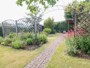 a garden with a fence and a brick path at Well Cottage in Cheltenham