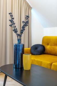 a blue vase on a table with a yellow couch at Smėlynas Boutique & SPA in Palanga