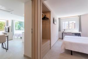 a white bedroom with a bed and a window at Halley Hotel & Apartments Affiliated by Meliá in Benidorm