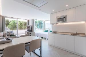 a kitchen with white cabinets and a table with chairs at Halley Hotel & Apartments Affiliated by Meliá in Benidorm