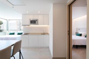 a kitchen with white cabinets and a table and a bed at Halley Hotel & Apartments Affiliated by Meliá in Benidorm
