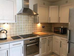 a kitchen with white cabinets and a microwave at Toothbrush Apartments - Ipswich Waterfront - Anchor St in Ipswich