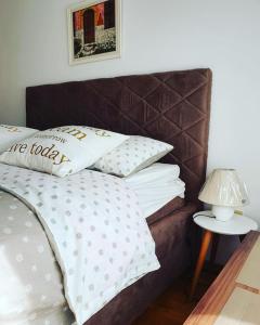 a bed with white pillows and a table with a lamp at Beauty apartment in Blue star complex Pržno Montenegro in Pržno