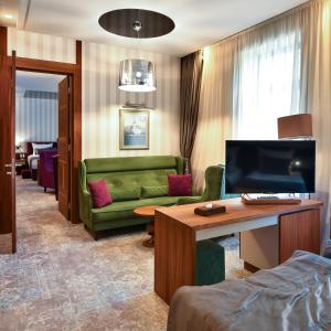 ein Wohnzimmer mit einem grünen Sofa und einem TV in der Unterkunft Heritage Hotel Krone in Sarajevo