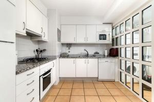Vila Sol Resort 2 Bedroom Family Apartment في كوارتيرا: مطبخ بدولاب بيضاء وأرضية بلاط