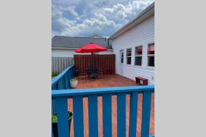 eine Terrasse mit einem roten Regenschirm, einem Tisch und einem Stuhl in der Unterkunft Beautiful 2 Bedroom Apartment in Shediac Bridge in Grande-Digue
