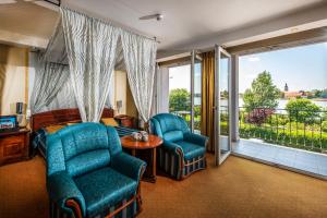a hotel room with a bed and chairs and a balcony at Duna Relax Hotel Ráckeve in Ráckeve