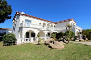 una grande casa bianca con palme in cortile di LEON INMO Apartment Denise - 10414 a Empuriabrava