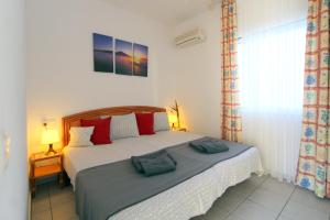 una camera da letto con un letto con cuscini rossi di LEON INMO Apartment Denise - 10414 a Empuriabrava Altre 15 foto