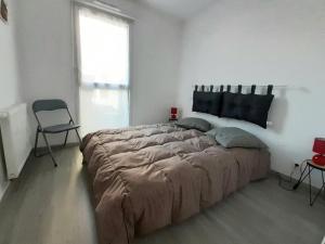 uma cama grande num quarto branco com uma cadeira em Appartement à 150m de la grande plage de Sion em Saint-Hilaire-de-Riez