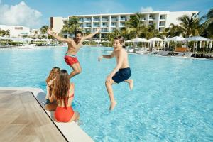 dois rapazes a saltar para uma piscina num resort em Grand Palladium Costa Mujeres Resort & Spa - All Inclusive em Cancún